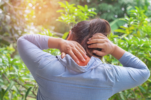 woman suffering from neck pain at outdoor. healthy concept